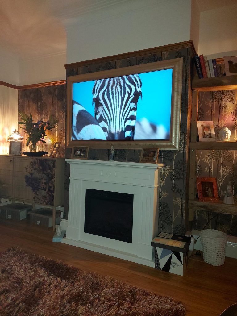 Modern Gold Framed Mirror TV over a fireplace 